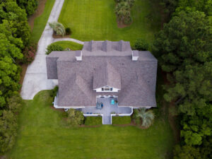 Aerial view of large home with new roof on beautiful property.